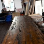 A close-up of a worn wooden table surface in a rustic room.