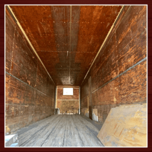 Empty wooden cargo truck interior with light at the end.