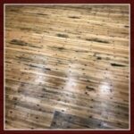 Wooden floor with dark spots and texture.